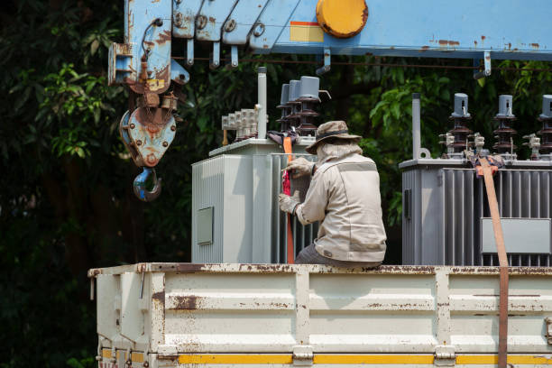 worker strapping power transformer on a truck